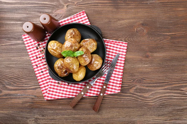 Zapečené brambory v pánvi na dřevěný stůl, pohled shora — Stock fotografie