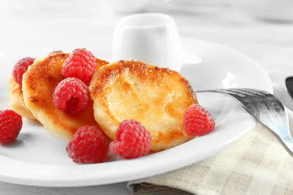 Krapfen von Hüttenkäse mit Himbeeren im Teller auf dem Tisch, Nahaufnahme — Stockfoto