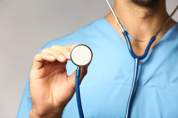 Doctor with stethoscope on grey background — Stock Photo, Image