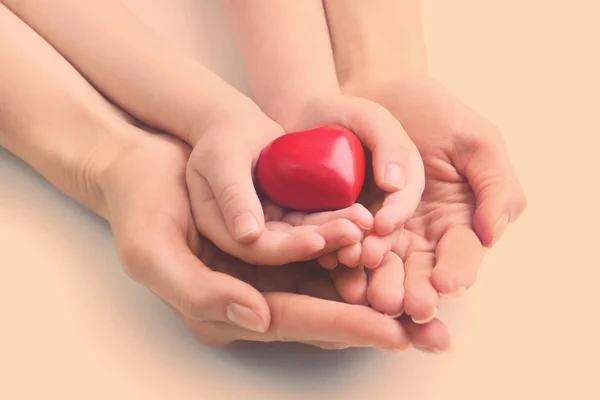 Corazón en manos de niño y madre sobre fondo claro — Foto de Stock