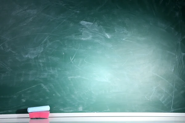 Blank blackboard with colored chalks and eraser. — Stock Photo, Image