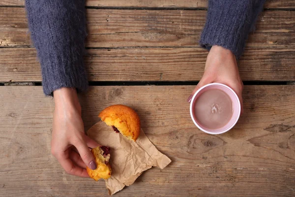 Жіночі руки тримають чашку кави та печива на дерев'яному столі крупним планом — стокове фото