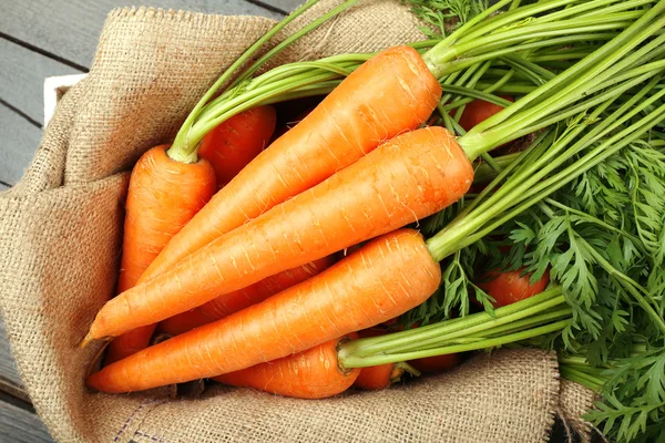 Fresh organic carrots on sackcloth, closeup — Stock Photo, Image