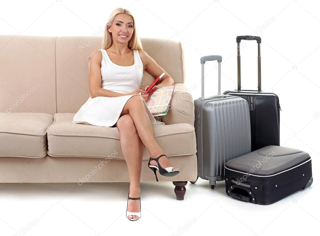 Woman with suitcase sitting on sofa 