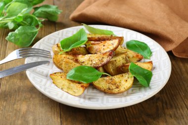 Ahşap masa, closeup üzerinde beyaz tabak içinde fesleğen yaprakları ile fırında patates