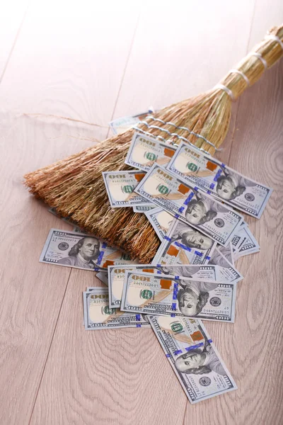 Dollars and broom on wooden floor, closeup — Stock Photo, Image