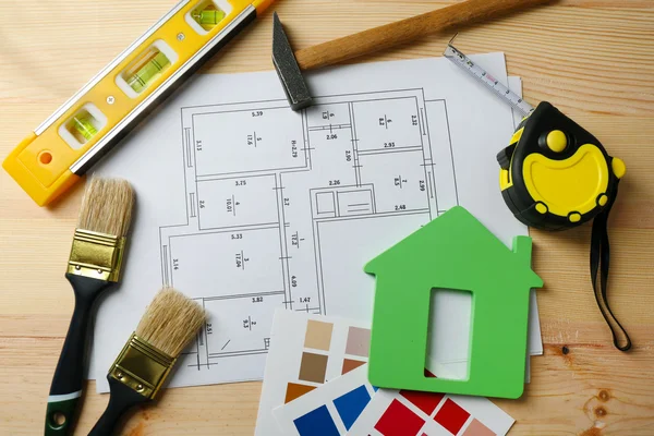 Instrumentos de construcción, plano y pinceles sobre fondo de mesa de madera — Foto de Stock