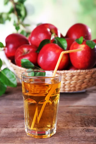 Glas äppeljuice med röda äpplen på träbord, närbild — Stockfoto