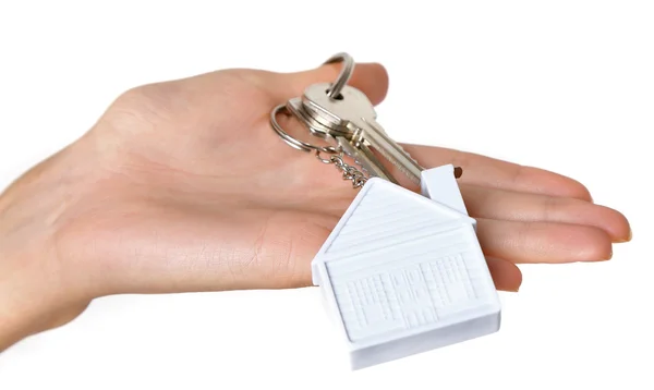 Γυναικείο χέρι που κρατά κλειδιά με μπρελόκ σπίτι σε φόντο λευκό τούβλο τοίχων — Φωτογραφία Αρχείου