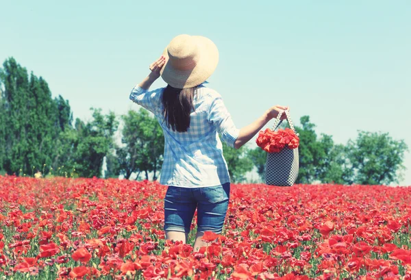 Woman walking with bag on poppy field over blue sky background — Stock Photo, Image