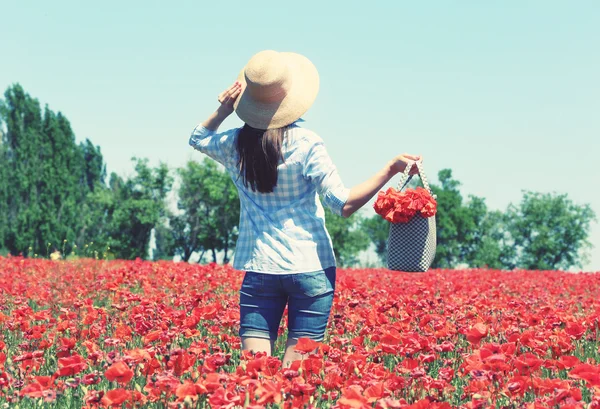 Mujer caminando con bolsa en el campo de amapola sobre fondo azul cielo —  Fotos de Stock