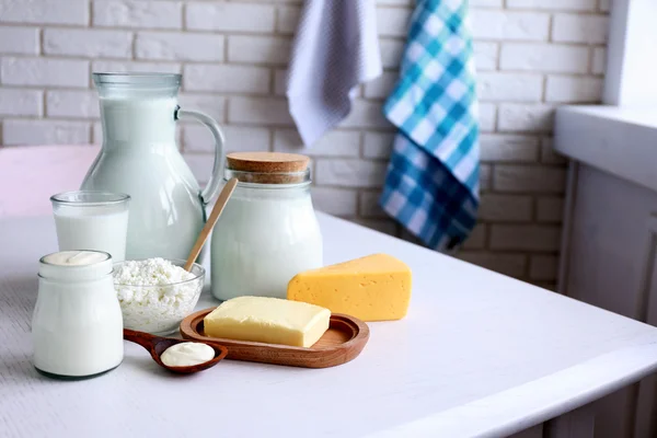 Productos lácteos sobre mesa de madera, sobre fondo de pared de ladrillo — Foto de Stock