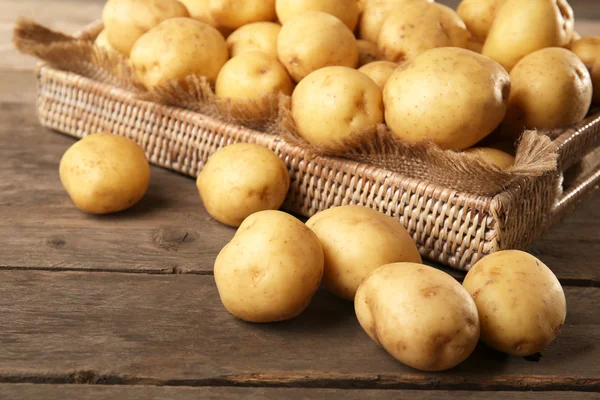 Nieuwe aardappelen in lade op houten tafel, close-up — Stockfoto