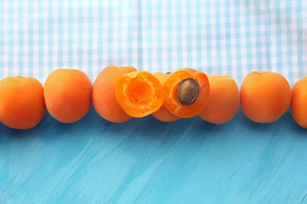 Спелые абрикосы с салфеткой на деревянном столе — стоковое фото