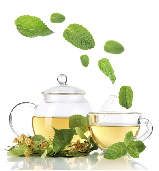 Bouilloire et tasse de thé avec tilleul et feuilles de menthe tombantes isolées sur blanc — Photo