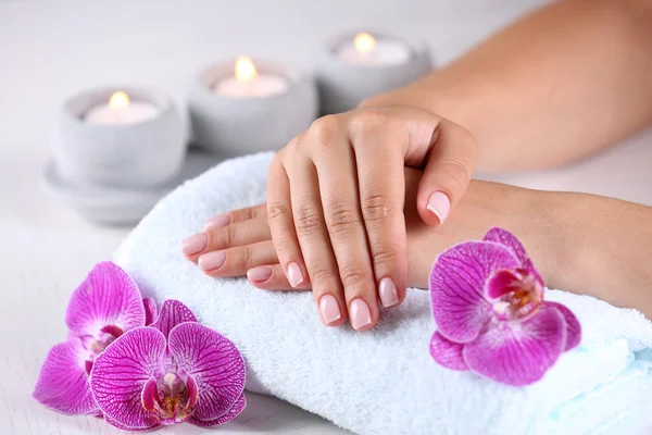 Handen met Frans manicure en orchid bloemen — Stockfoto
