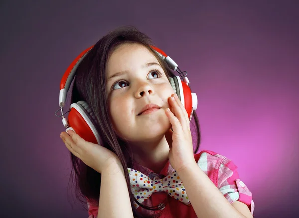 漂亮的小女孩，在彩色背景上听音乐 — 图库照片