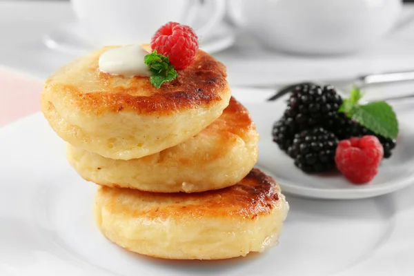 Fritters of cottage cheese with berries in plate on table, closeup — Stock Photo, Image