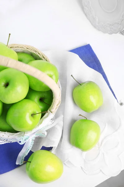 Green apples in wicker basket on table with napkin, closeup — Stock Photo, Image