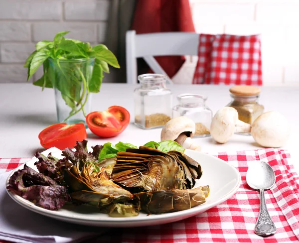 Roasted artichokes on plate, on kitchen table background — Stock Photo, Image