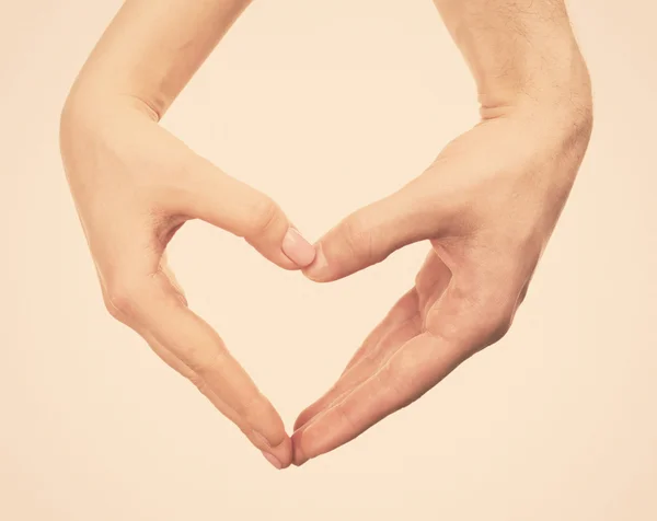 Heart shaped by male and female hands on light background — Stock Photo, Image