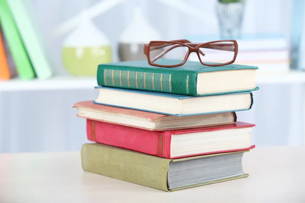 Montón de libros con vasos sobre mesa de madera en la habitación —  Fotos de Stock