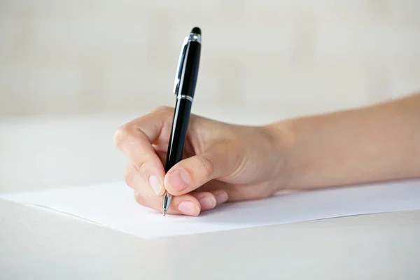 Mano femminile con penna scritta su carta sul posto di lavoro — Foto Stock