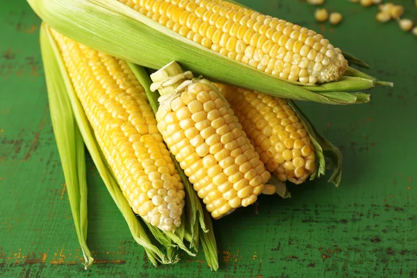 Fresh corn on cobs on green wooden background — Stock Photo, Image