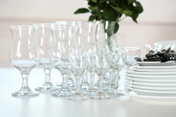 Čisté talíře, sklenice a příbory na bílém stole — Stock fotografie