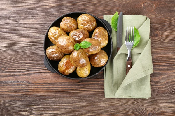 Patatas al horno en sartén sobre mesa de madera, vista superior —  Fotos de Stock