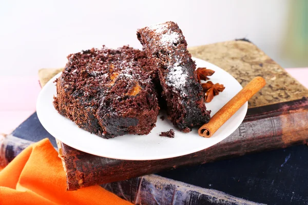 Delicioso rollo de chocolate en platillo en libro, primer plano — Foto de Stock