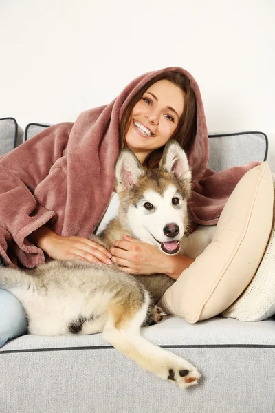 Divan malamute köpekle yatan kadın — Stok fotoğraf