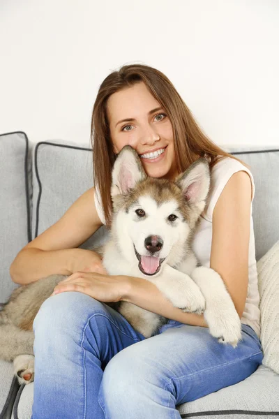 Kvinna med hennes malamute hunden på soffa — Stockfoto