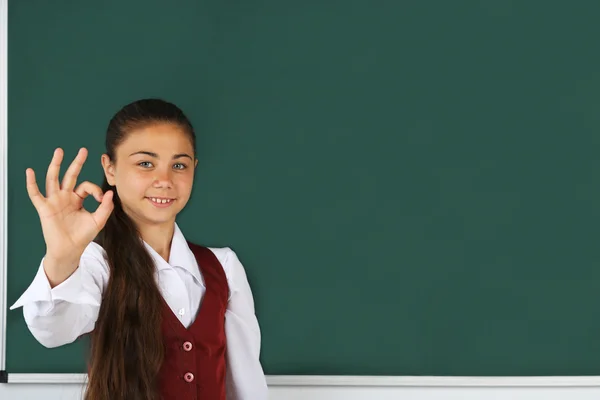 Liten flicka står nära blackboard — Stockfoto