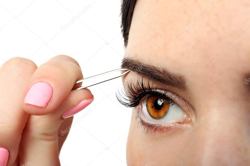Young woman plucking eyebrows 