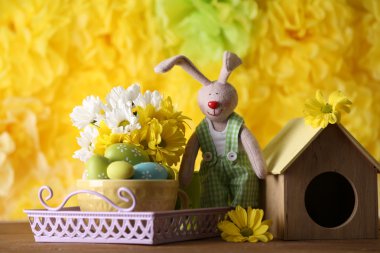 Paskalya tavşanı Sarı zemin üzerine ahşap masaya çiçek ile boyalı Paskalya yumurtaları ile