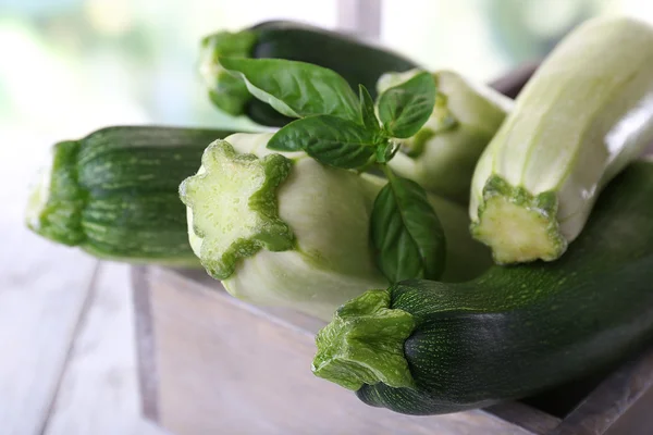Fresh zucchini with squash and basil in wooden box on bright background — Stock Photo, Image