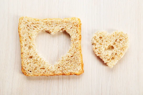 Krajíc chleba s řez ve tvaru srdce na dřevěné pozadí — Stock fotografie