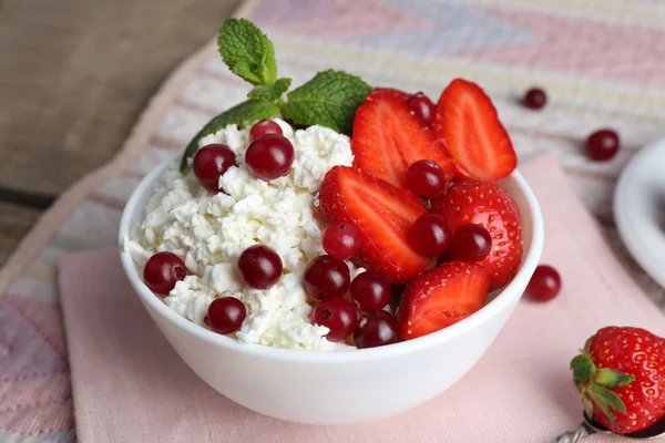 Bowl of cottage cheese with strawberry and cranberry on table, closeup — Stock Photo, Image