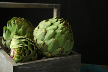 Enginar koyu arka plan üzerinde ahşap sepeti