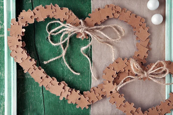 Puzzle hecho en forma de corazones sobre fondo de madera de color — Foto de Stock