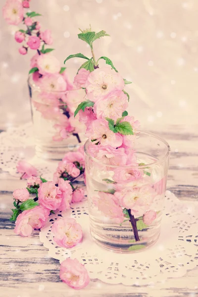 Mooie fruit blossom in glazen op tafel op lichte achtergrond — Stockfoto