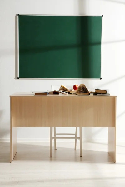 Escritorio escolar con libros y manzana roja en el aula — Foto de Stock