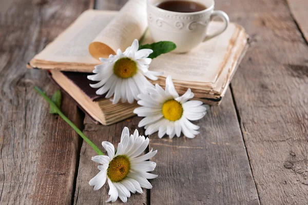 Libro viejo con hermosas flores y taza de té en la mesa de madera de cerca —  Fotos de Stock