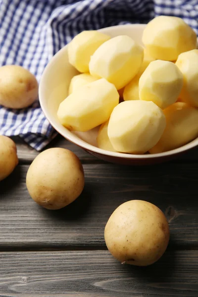 Patate pelate nuove in ciotola su tavolo di legno con tovagliolo, primo piano — Foto Stock