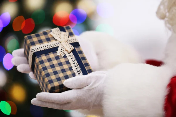 Santa segurando presente no fundo da árvore de Natal — Fotografia de Stock