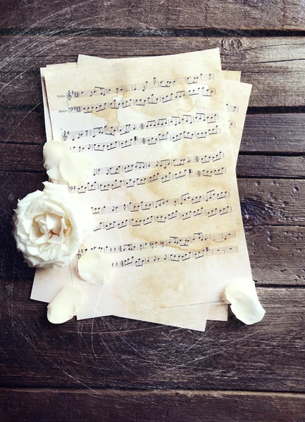 Bela rosa em folhas de música na mesa de madeira — Fotografia de Stock