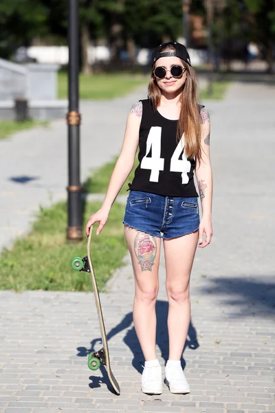 Mooie getatoeëerd meisje met skateboard, buitenshuis — Stockfoto