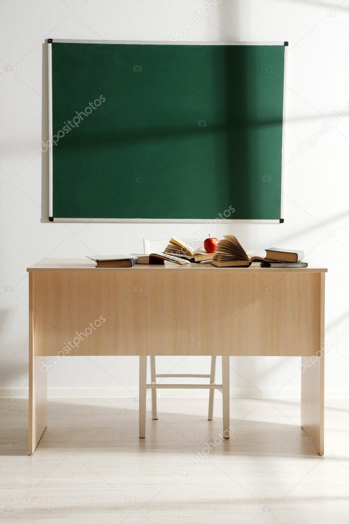 School desktop with books and red apple at classroom