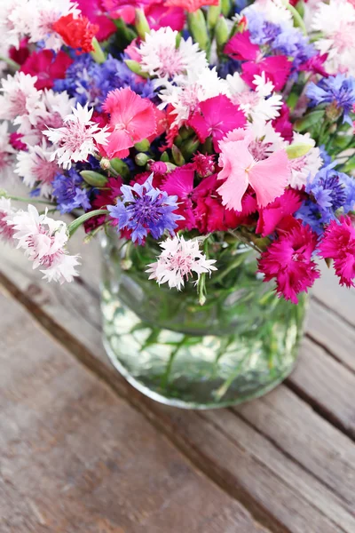 Krásné malé kytice ve váze na dřevěné pozadí — Stock fotografie